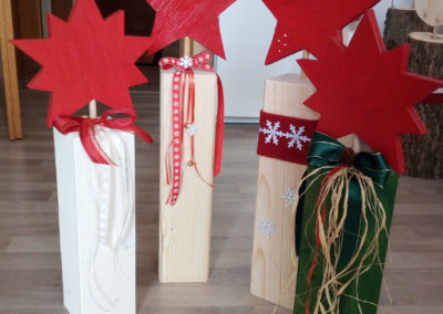 Dekorative Holzbalken mit Sternen, Filzband und Schleifen in verschiedenen Farben und Bändern und Bast.