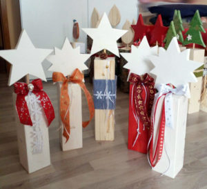 Dekorative Holzbalken mit Sternen, Filzband und Schleifen in verschiedenen Farben und Bändern