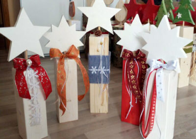 Dekorative Holzbalken mit Sternen, Filzband und Schleifen in verschiedenen Farben und Bändern