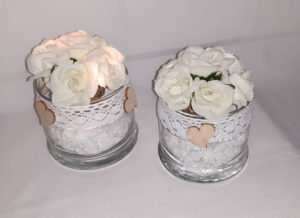 Dekaoratives Glas mit weißen Steinen, Weidenkugel mit weißen Rosenblüten, Lichterketteund Spitzenbordüre