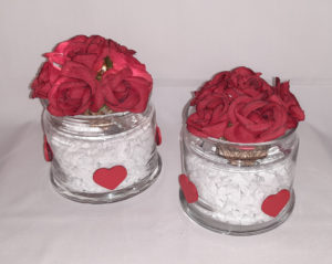 Dekaoratives Glas mit weißen Steinen, Weidenkugel mit roten Rosenblüten und Lichterkette